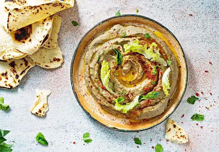 Bļoda ar Baba Ghanoush mērci bļodā ar pitas maizes gabaliņiem apkārt